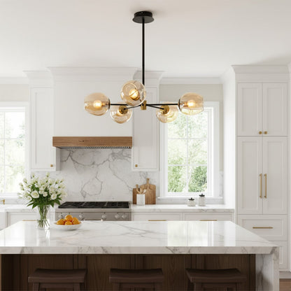 Modern chandelier with glass globe lights in gold finish hanging above kitchen island adding warm ambient lighting to elegant home interior.