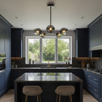Contemporary chandelier with metal frame and glass globes suspended over kitchen island creating balanced illumination and refined decor style.