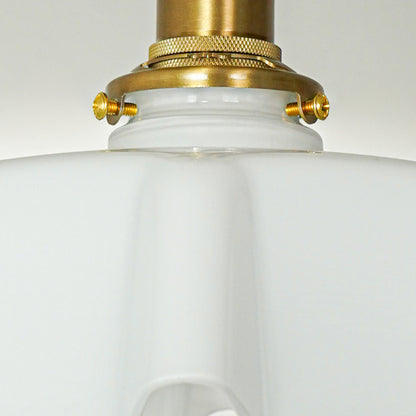 Closeup of white glass shade and gold metal fixture for premium ceiling lighting and refined decor styling spaces.