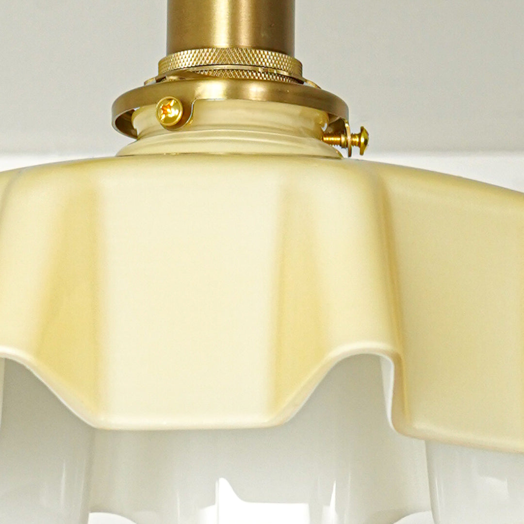 Closeup of cream glass shade and gold metal fixture for premium ceiling lighting and luxury decor styling spaces.