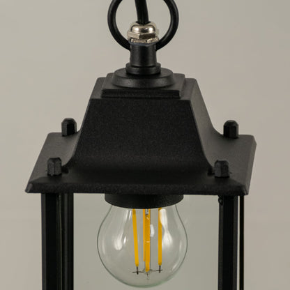 A closeup view of the black outdoor lantern with light on highlighting the warm bulb glow and clean transparent glass panels for enhanced visual clarity.