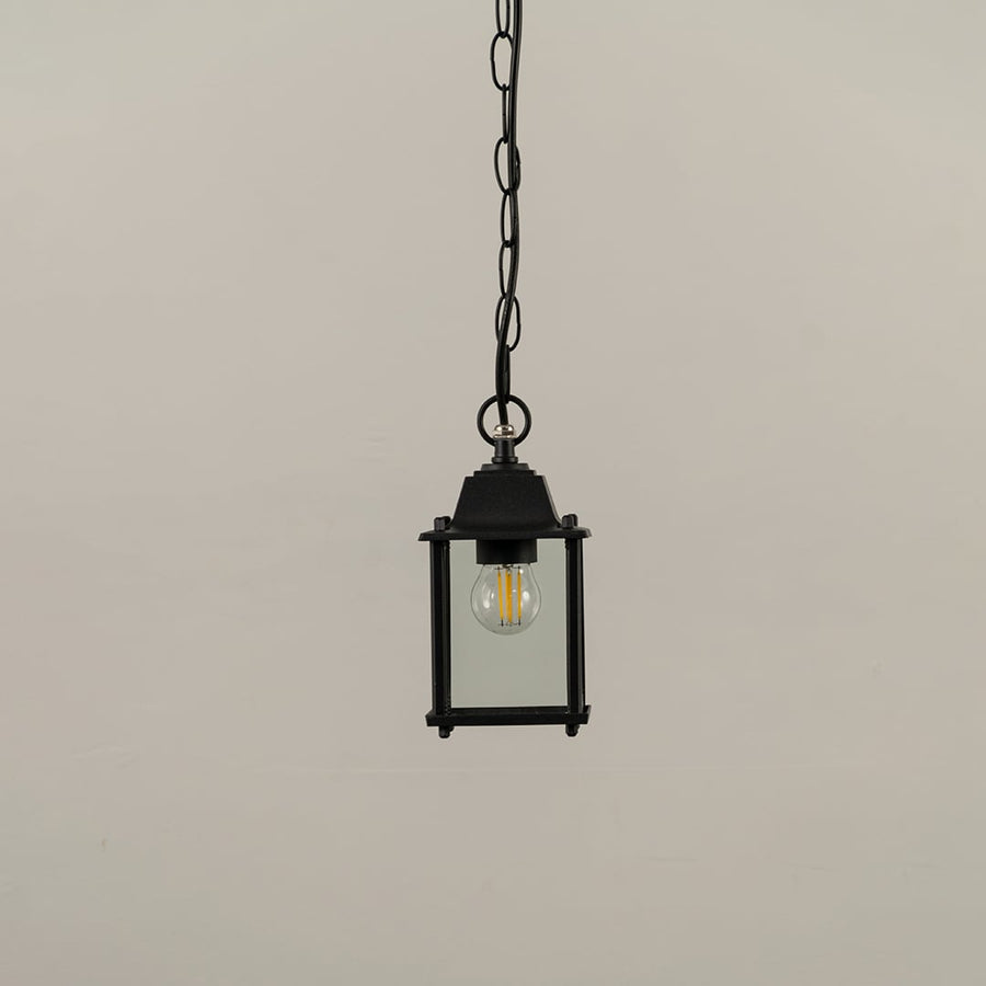 A black square hanging lantern on white background with light off showing clear glass and simple clean metal frame perfect for modern outdoor decor.