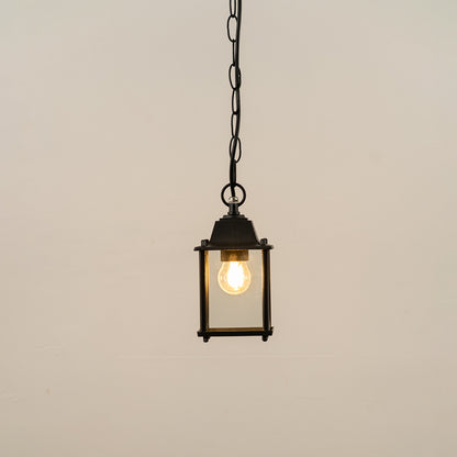 Black metal hanging outdoor lantern with square glass enclosure glowing on white background suitable for porch entrance and exterior decor lighting.