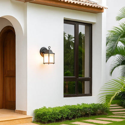 A soft glowing outdoor wall lantern mounted beside a bright white house entrance illuminating the walkway with a warm light that enhances the modern exterior ambiance.