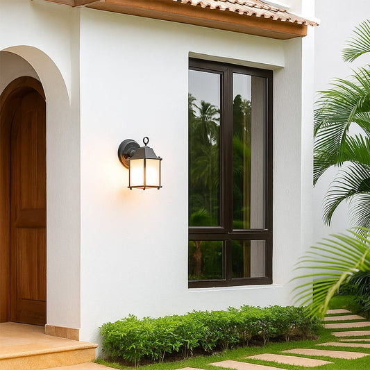 A soft glowing outdoor wall lantern mounted beside a bright white house entrance illuminating the walkway with a warm light that enhances the modern exterior ambiance.