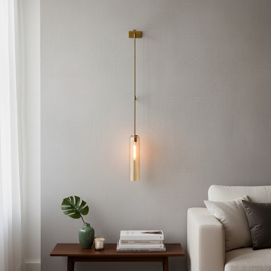 Modern wall pendant light with gold metal arm and warm glowing tube shade styled beside sofa for cozy living room decor.