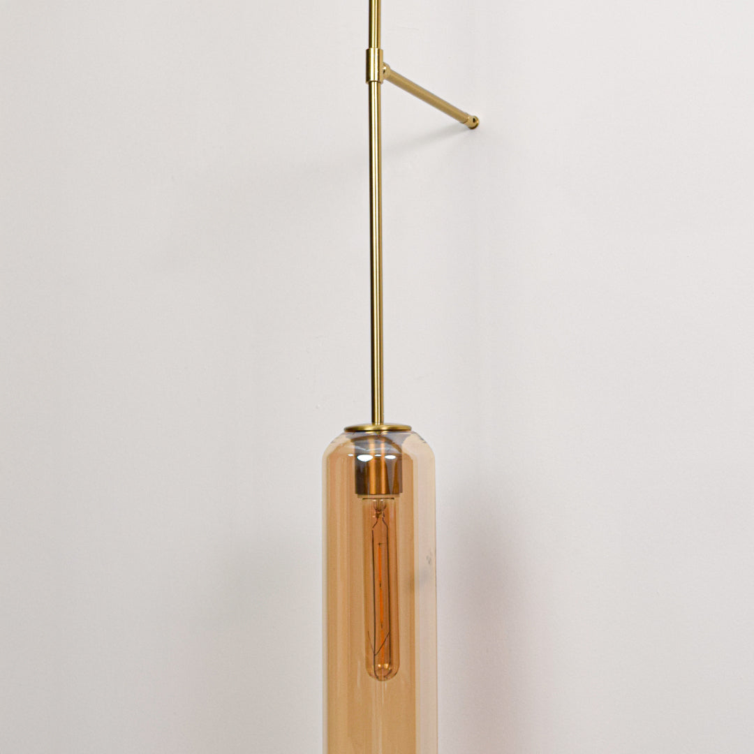 Closeup of gold metal wall light with cylindrical tube shade showcasing sleek design and warm lighting for interior decor styling.