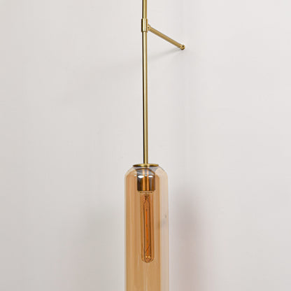 Closeup of gold metal wall light with cylindrical tube shade showcasing sleek design and warm lighting for interior decor styling.