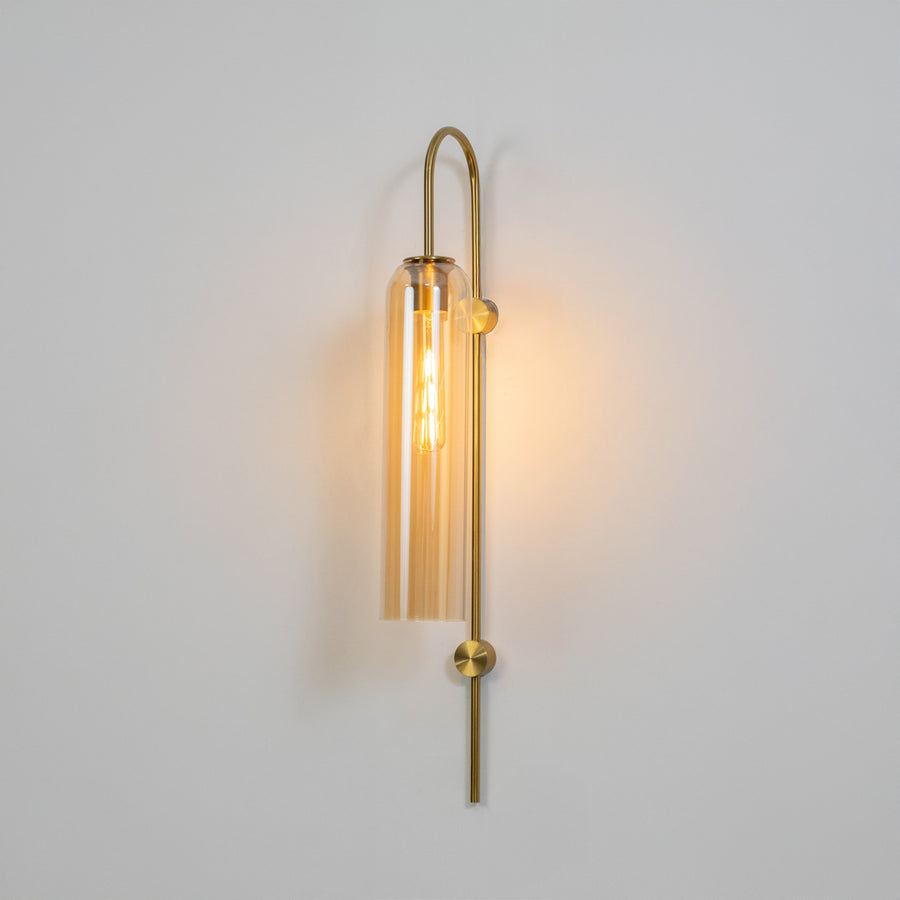 Modern gold metal wall light with clear glass shade for stylish bedroom and premium decor spaces.