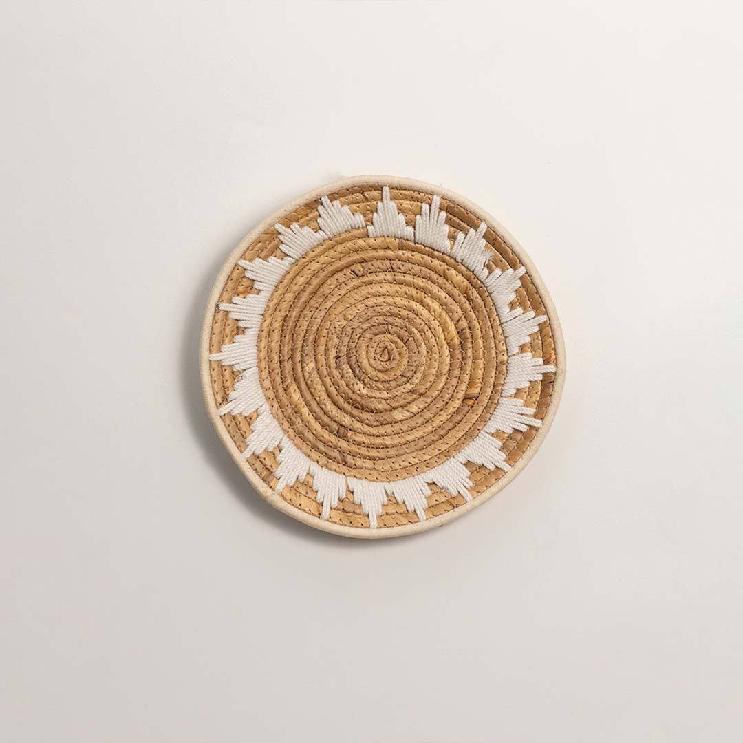 Round handcrafted natural seagrass wall basket with geometric pattern on white background image.