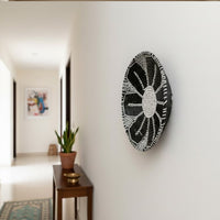 Round wall decor in dark tone mounted along hallway wall enhancing contemporary home styling with artistic and elegant appeal.