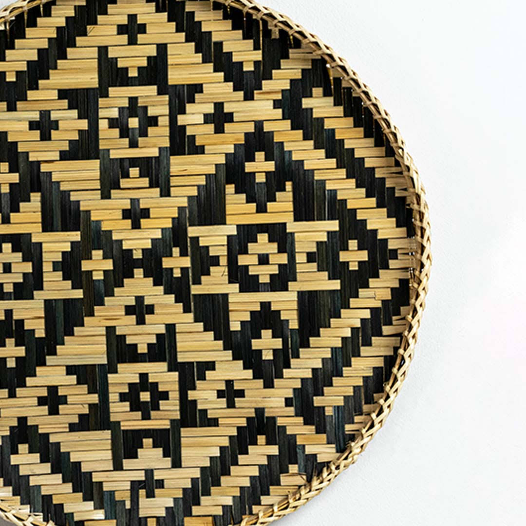 Closeup of handcrafted black and natural seagrass wall basket with diamond woven pattern for artisan home décor styling.
