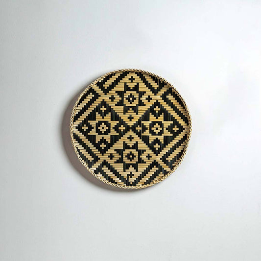 Round handcrafted black and natural seagrass wall basket with diamond pattern on white background image.