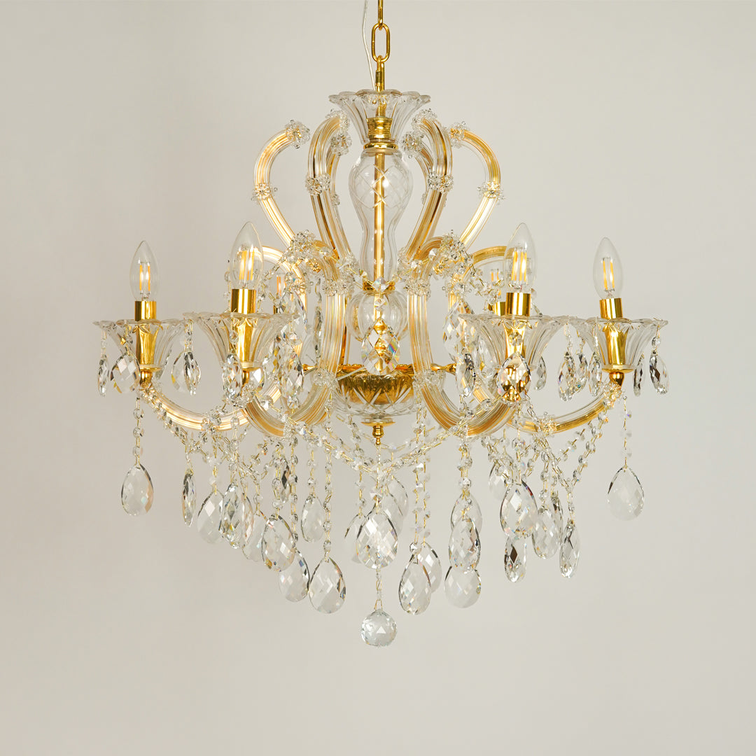 White background image of gold metal candle style chandelier for elegant dining room decor styling with unlit crystal arms.