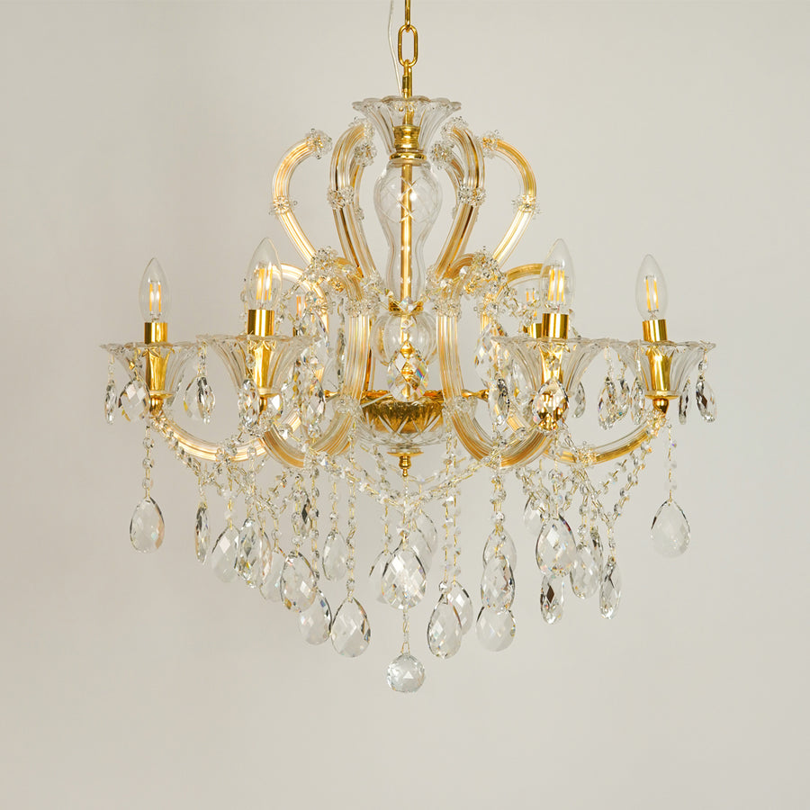 White background image of gold metal candle style chandelier for elegant dining room decor styling with unlit crystal arms.