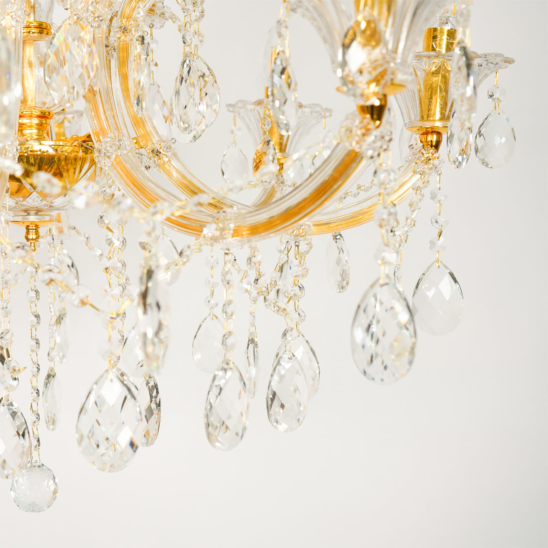 Closeup image of large gold metal candle style chandelier for modern dining room decor styling with elegant crystal detailings.