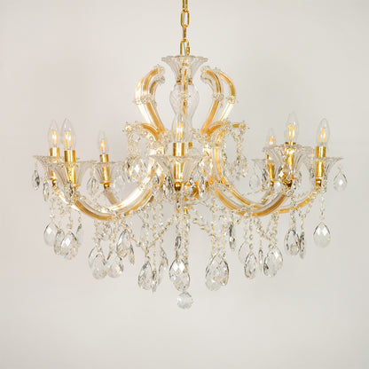 White background image of large gold metal candle style chandelier for elegant dining room decor with unlit crystal arms.
