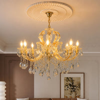 Lifestyle image of large gold metal candle style chandelier for luxury dining room decor styling with crystal detailings.