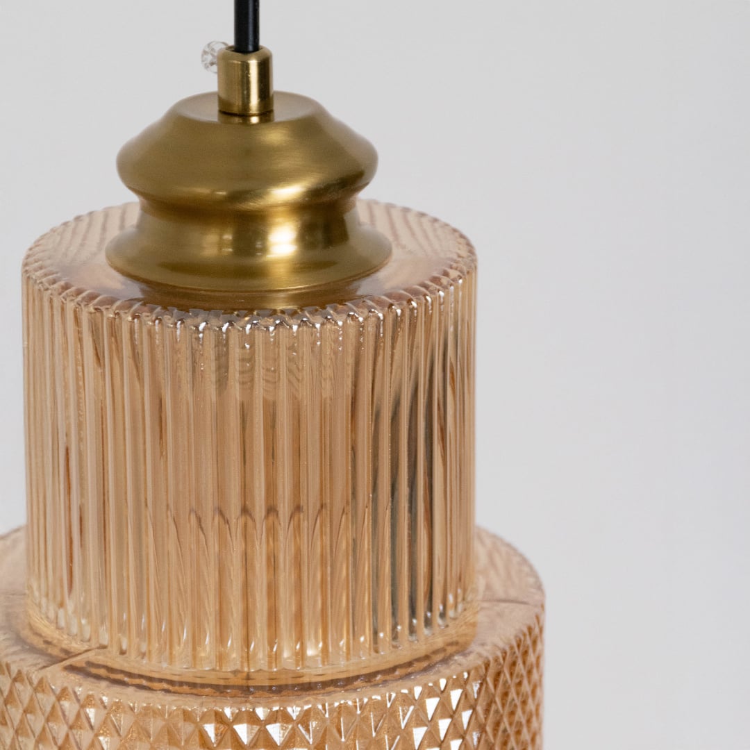 Closeup view of pendant light with ribbed glass shade and brass finish showing modern detail for home decor.