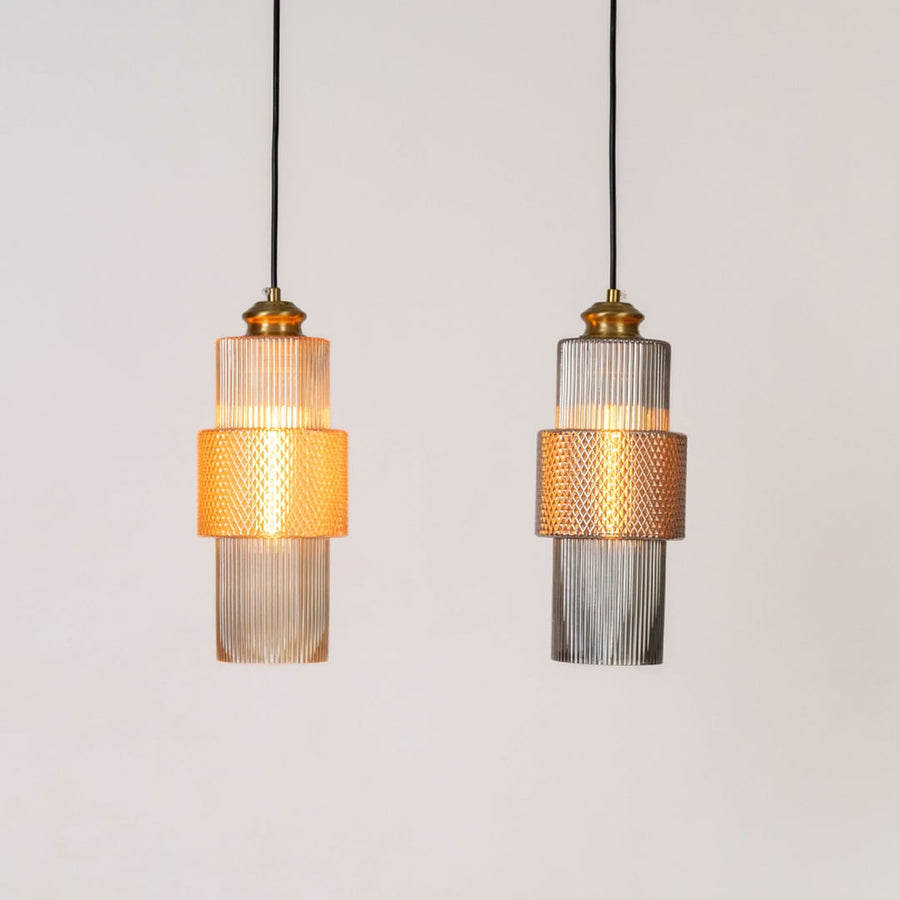 Pair of pendant lights with ribbed glass and brass finish glowing warmly on white background for ceiling lighting.