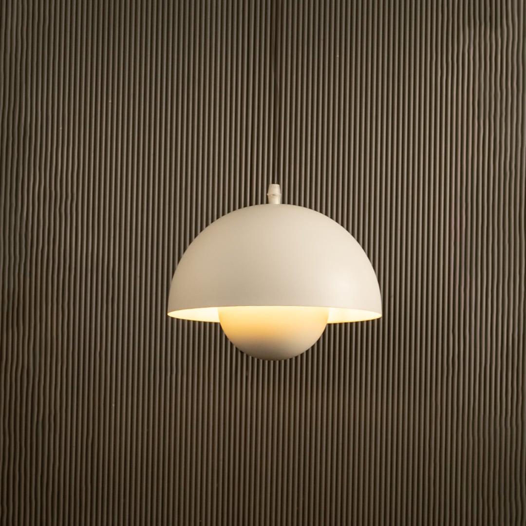 White dome pendant light glowing softly against black background with a neutral wall highlighting its sleek modern form.