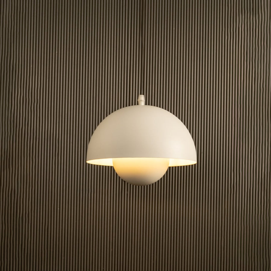 White dome pendant light glowing softly against black background with a neutral wall highlighting its sleek modern form.