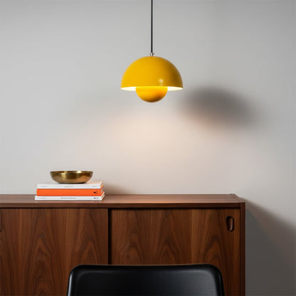 Set of dome pendant lights in orange grey and mustard tones hanging above a wooden table with a cozy sofa creating a warm inviting atmosphere.