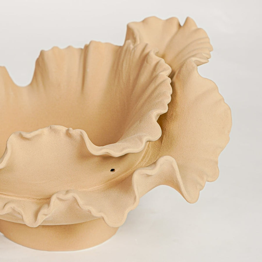 Detailed closeup of beige ceramic ruffled bowl showcasing sculpted organic curves and refined textured surface.