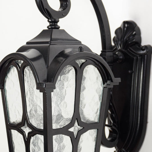 Closeup of black exterior wall lantern showcasing ornate arm detailing textured glass panels and sturdy metal frame.