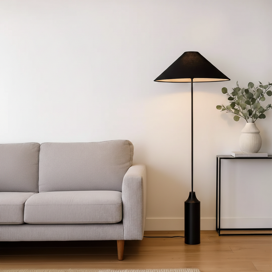 Floor lamp styled beside sofa and wooden side table in warm living room setting showing soft ambient glow modern shade and sculpted base.