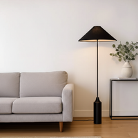 Floor lamp styled beside sofa and wooden side table in warm living room setting showing soft ambient glow modern shade and sculpted base.