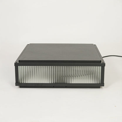 Contemporary black outdoor wall light with horizontal ribbed glass design on clean background ideal for patio or garden lighting.

