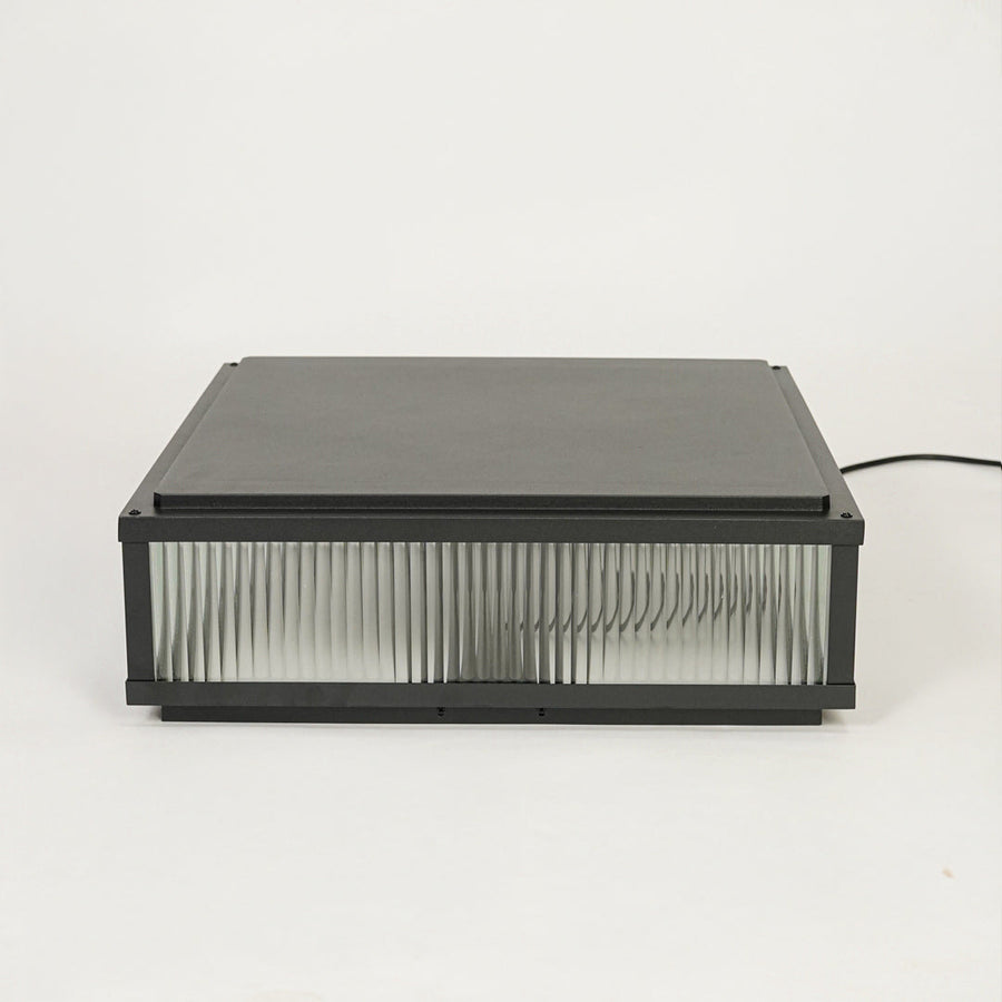 Contemporary black outdoor wall light with horizontal ribbed glass design on clean background ideal for patio or garden lighting.

