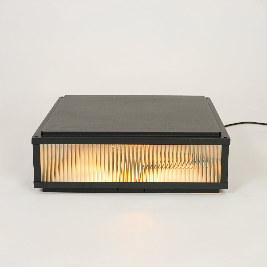 Minimal rectangular outdoor wall light with ribbed glass shade mounted on neutral wall background perfect for modern exterior decor lighting.