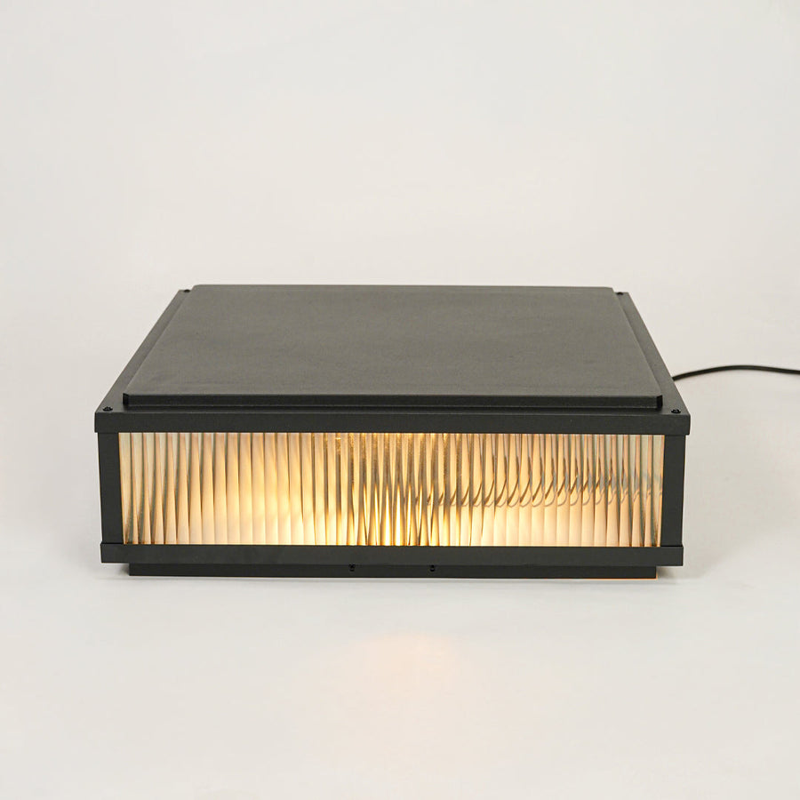 Minimal rectangular outdoor wall light with ribbed glass shade mounted on neutral wall background perfect for modern exterior decor lighting.