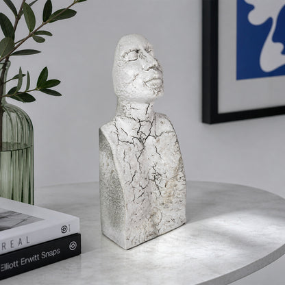 White textured resin face sculpture placed on table beside plant for elegant modern home decor styling.