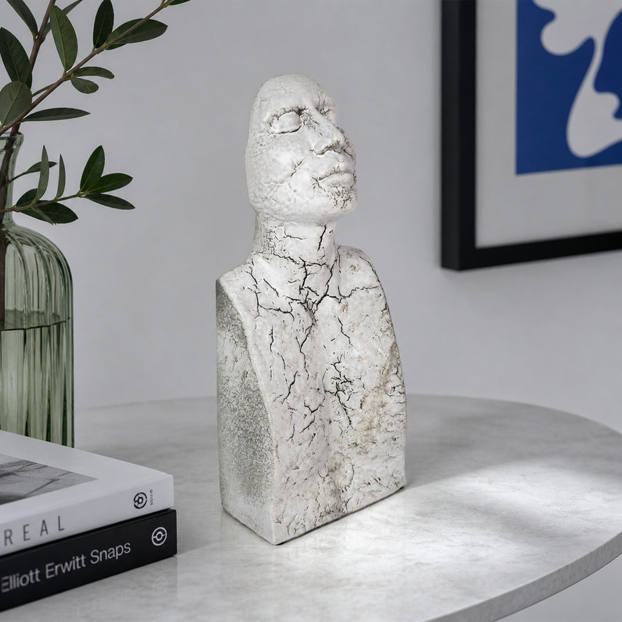 White textured resin face sculpture placed on table beside plant for elegant modern home decor styling.