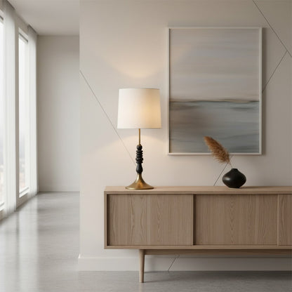 Contemporary table lamp featuring a white fabric shade black stacked decorative base and metal stand offering warm ambient illumination for interior home decor.