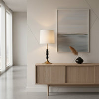 Contemporary table lamp featuring a white fabric shade black stacked decorative base and metal stand offering warm ambient illumination for interior home decor.