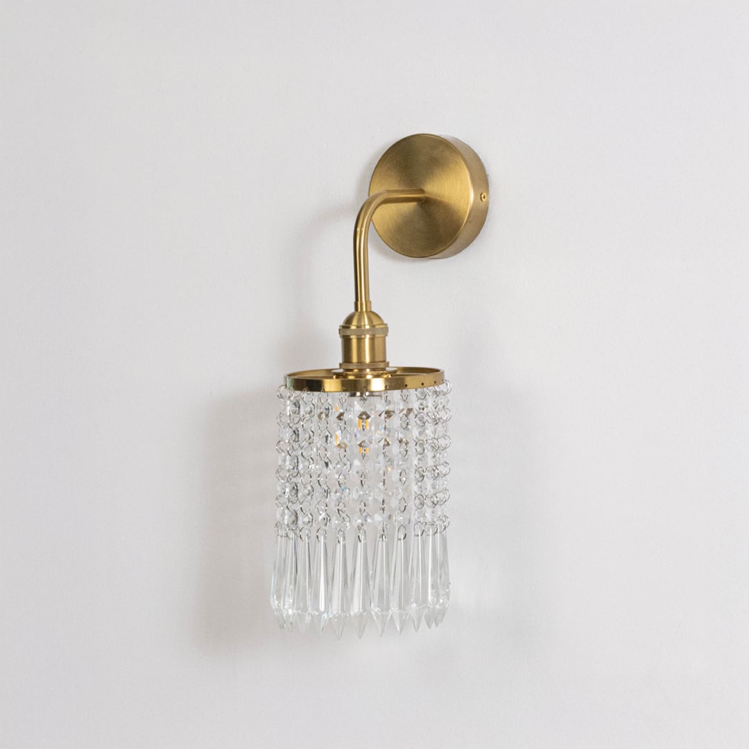 Gold metal crystal wall light on white background with transparent crystal detailing for stylish bedroom wall decor.