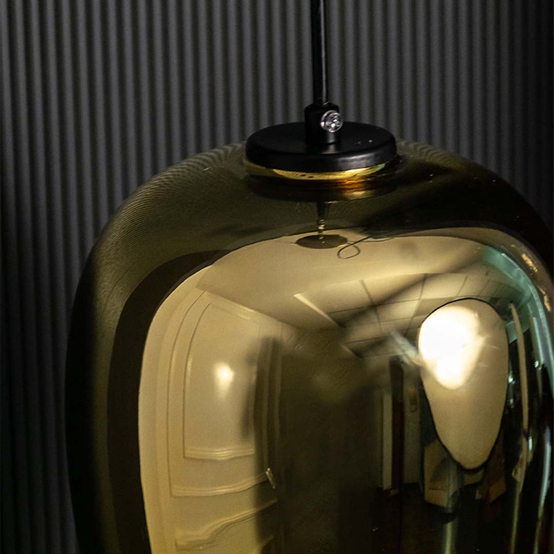 A closeup of the amber tinted glass pendant light highlighting its warm glowing bulb and smooth curved teardrop shaped glass body.