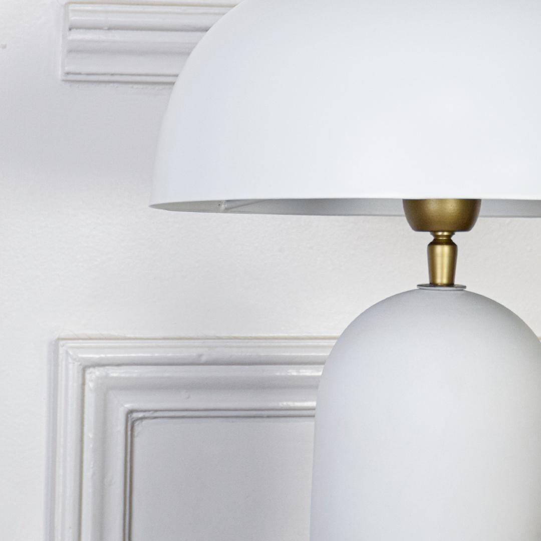 Table lamp closeup showing smooth white dome shade warm internal glow and soft curved base texture highlighting refined craftsmanship and elegant finish.
