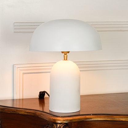 Table lamp displayed on clean white background highlighting rounded white dome shade matte body and brass detail showing modern minimalist design appeal.