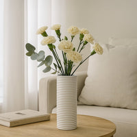 Tall white ribbed ceramic vase with dried pampas stems placed on neutral background adding elegant minimalist home decor.
