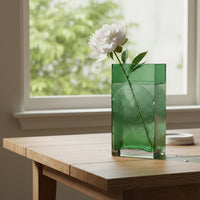 Green glass decorative vase styled with fresh flowers near a window for contemporary home decor and table styling.