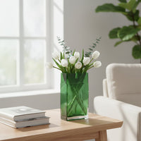 Green glass decorative vase styled with white flowers on a wooden table for elegant contemporary home decor settings.