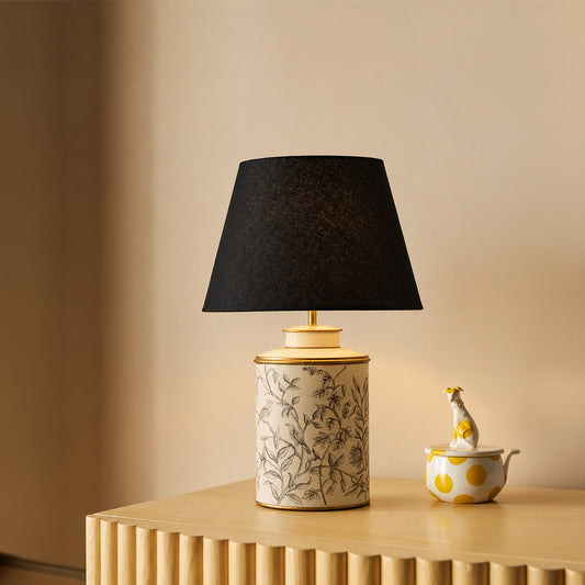 White floral ceramic table lamp with black fabric shade creating cozy ambient lighting in refined contemporary interiors.