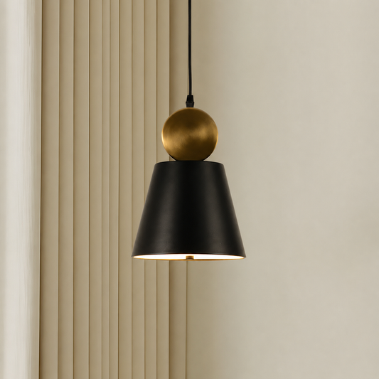 A modern pendant light with a matte black conical shade and a brushed gold spherical accent, hanging against a beige wall with vertical slats.