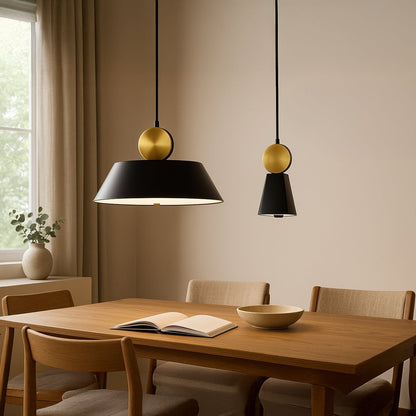 Modern pendant light showcased in a clean lifestyle setting with a matte black tapered shade and a brushed gold sphere accent on top.
