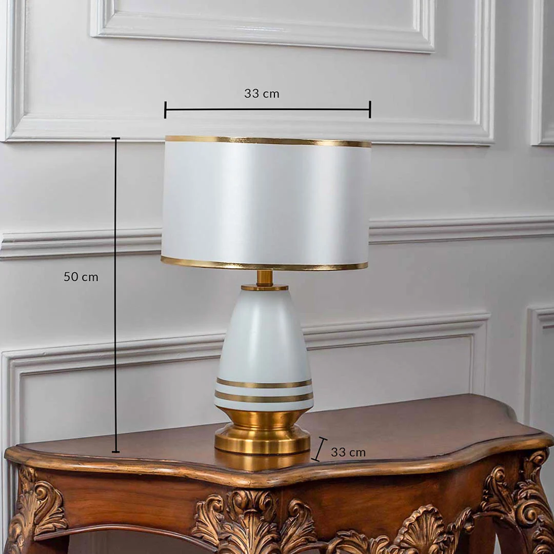 White shade gold and white table lamp with size 52cm height and 33cm width placed on carved console table with light off for modern elegant décor.